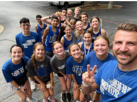 Coach Gleason poses with Cross Country team at the Cushing meet.
